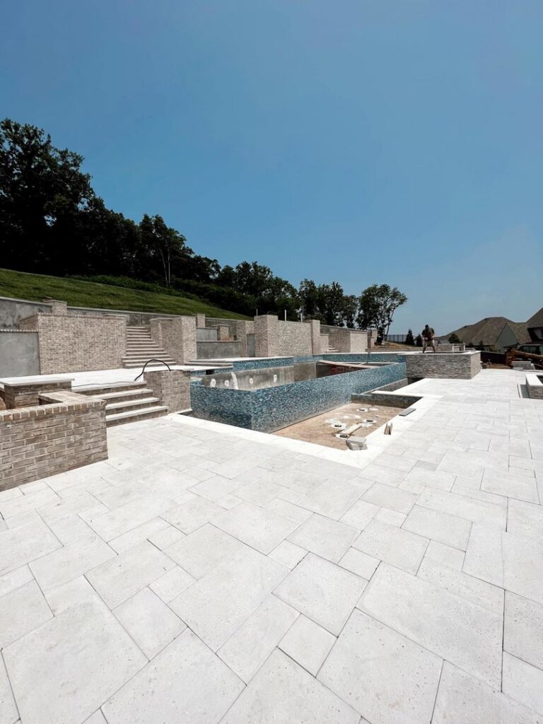 A large pool and hardscape area under construction, featuring brick walls and blue mosaic tiling, by Creative Pools and Hardscape in Franklin, TN.