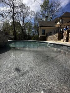 A close-up view of a swimming pool interior, showcasing the pebble finish and steps, installed by Picasso Poolscapes in Johns Creek, GA.