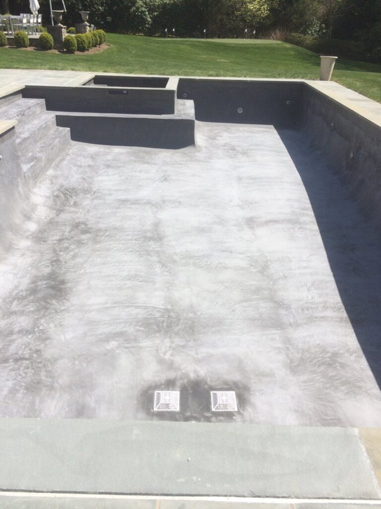 An empty swimming pool with a newly installed dark grey liner or plaster, indicating renovation work by B-rod Pool Service LLC in Norwalk, CT.