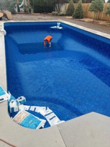 A worker installing or adjusting a pool liner inside an empty pool, demonstrating expert service from Creative Pools and Hardscape in Franklin, TN.