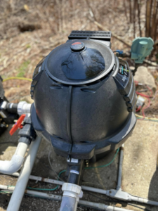 A close-up view of a black pool pump and filter system, maintained by B-rod Pool Service LLC in Norwalk, CT.