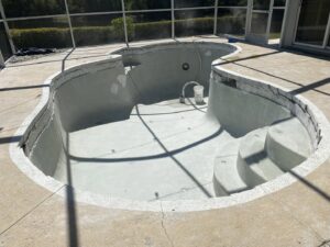 An empty pool undergoing renovation with its shell exposed, showcasing a general contractor job by JJB Pools & Spas in Tampa, FL.