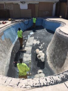 Workers preparing a swimming pool for resurfacing or cleaning by Top Notch Sandblasting LLC in Randallstown, MD