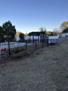 A newly installed black metal fence providing safety around a pool area by Fence & Deck Connection, Inc. in Savannah, GA.