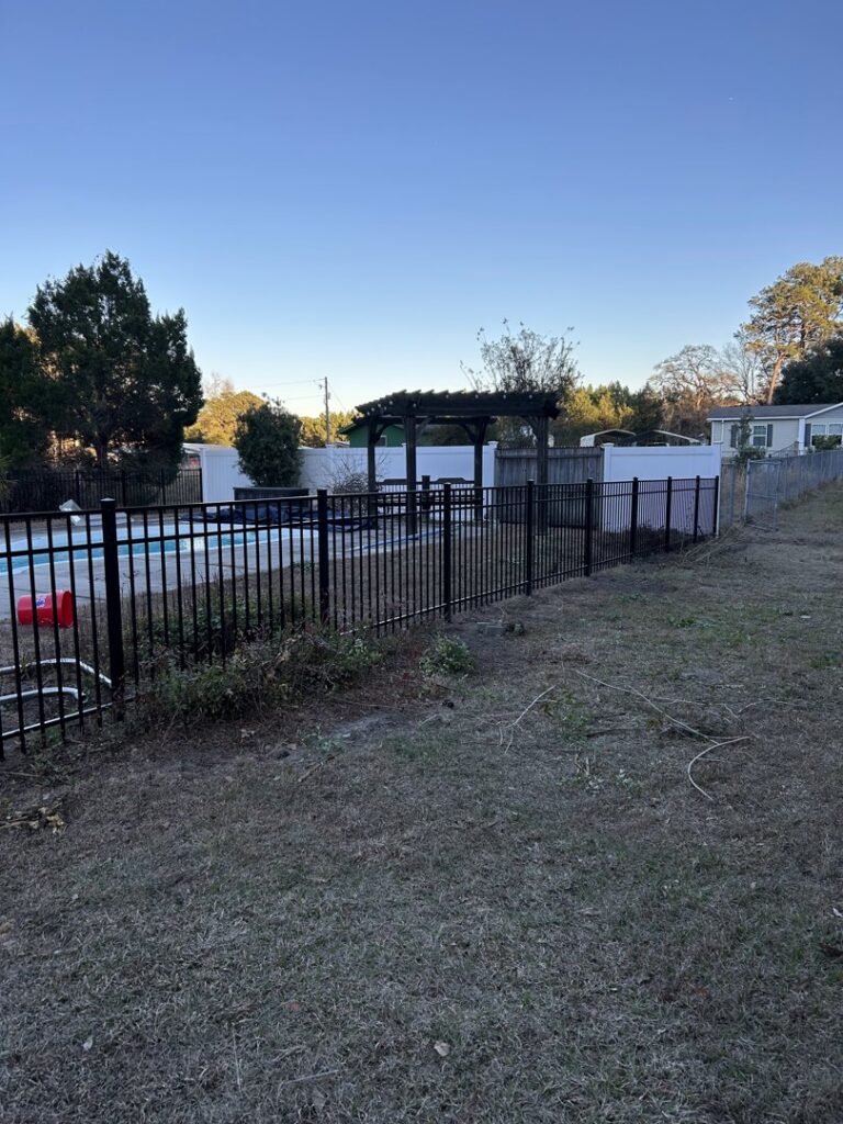 A newly installed black metal fence providing safety around a pool area by Fence & Deck Connection, Inc. in Savannah, GA.