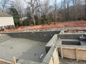The interior of a concrete pool shell showing plumbing pipe openings and surrounding formwork by Ga Impact Shotcrete in Atlanta, GA.