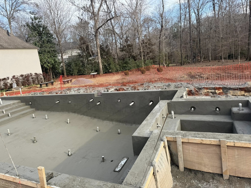 The interior of a concrete pool shell showing plumbing pipe openings and surrounding formwork by Ga Impact Shotcrete in Atlanta, GA.