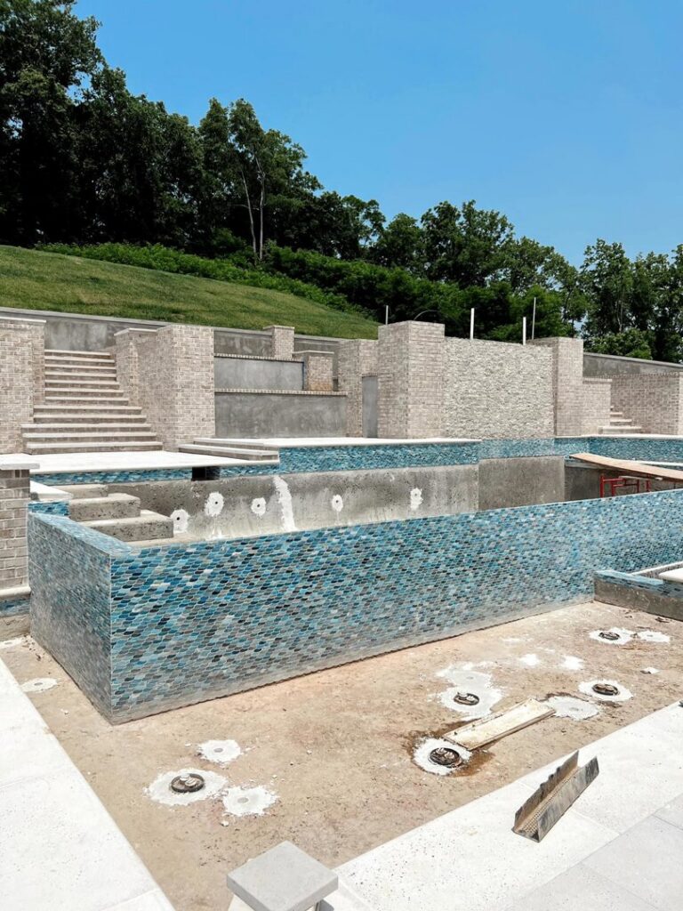 Close-up view of blue mosaic tiles being expertly installed on pool walls by Creative Pools and Hardscape in Franklin, TN.