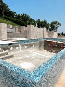 Pool construction in progress, showing blue mosaic tiling being applied to the pool walls with scaffolding, by Creative Pools and Hardscape in Franklin, TN.