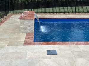 A beautiful pool waterfall feature with natural stone patio installed by Southern Pool Solutions in Knoxville, TN.