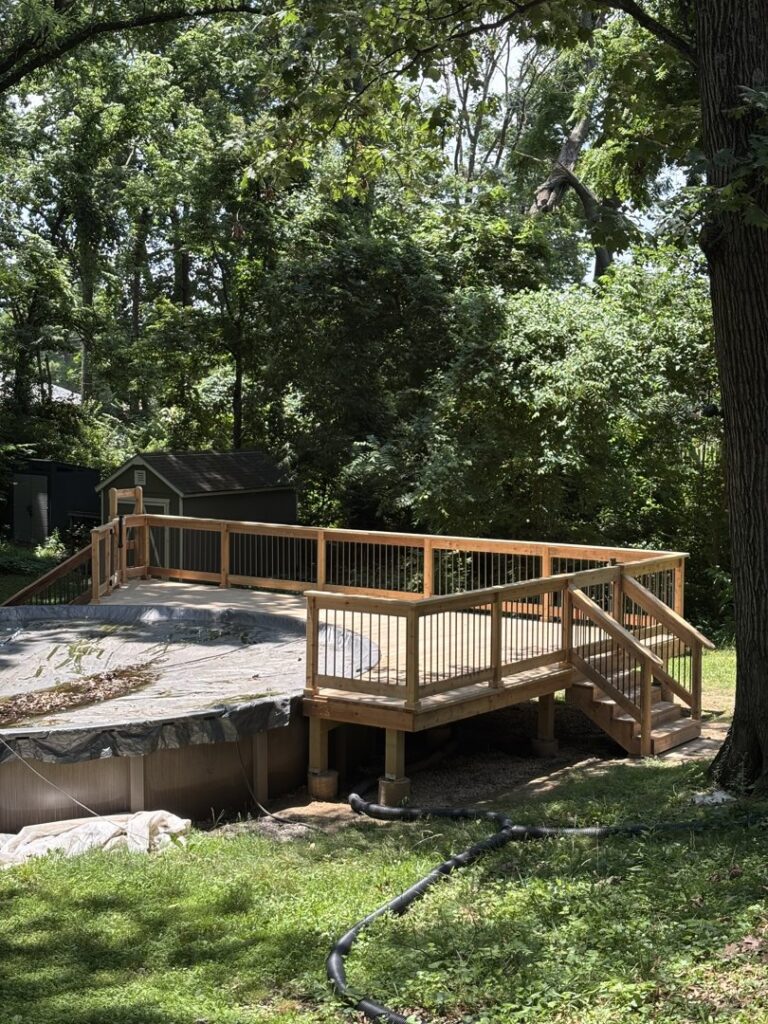 A newly installed wooden deck with railings next to an above-ground pool, a project by McIntosh Construction in Des Peres, MO.