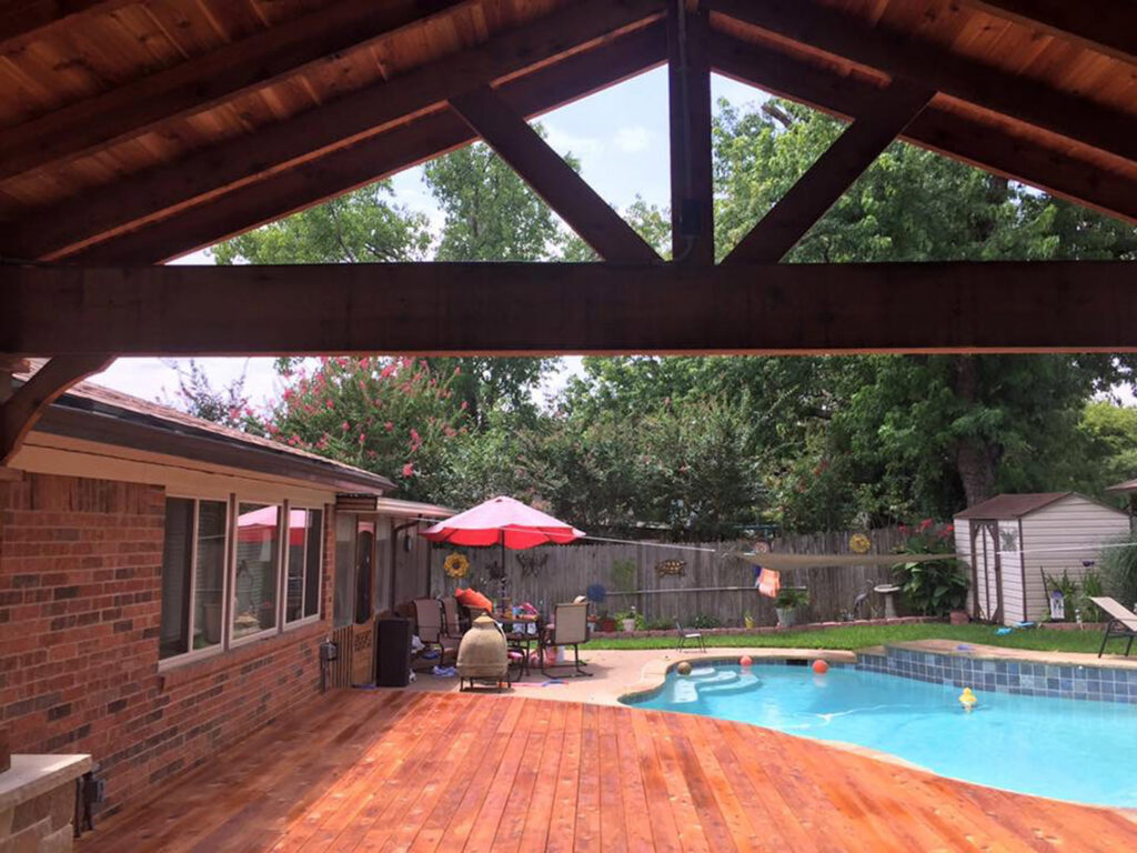 A custom poolside patio cover and pergola built by Tin Star Fencing, creating a shaded area in Fort Worth, TX