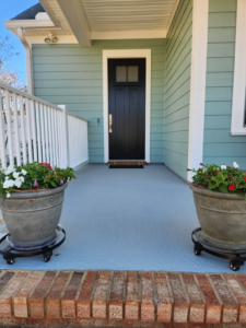 Freshly painted porch floor and black front door on a blue house by Oseguera Painting, LLC in Tallahassee, FL