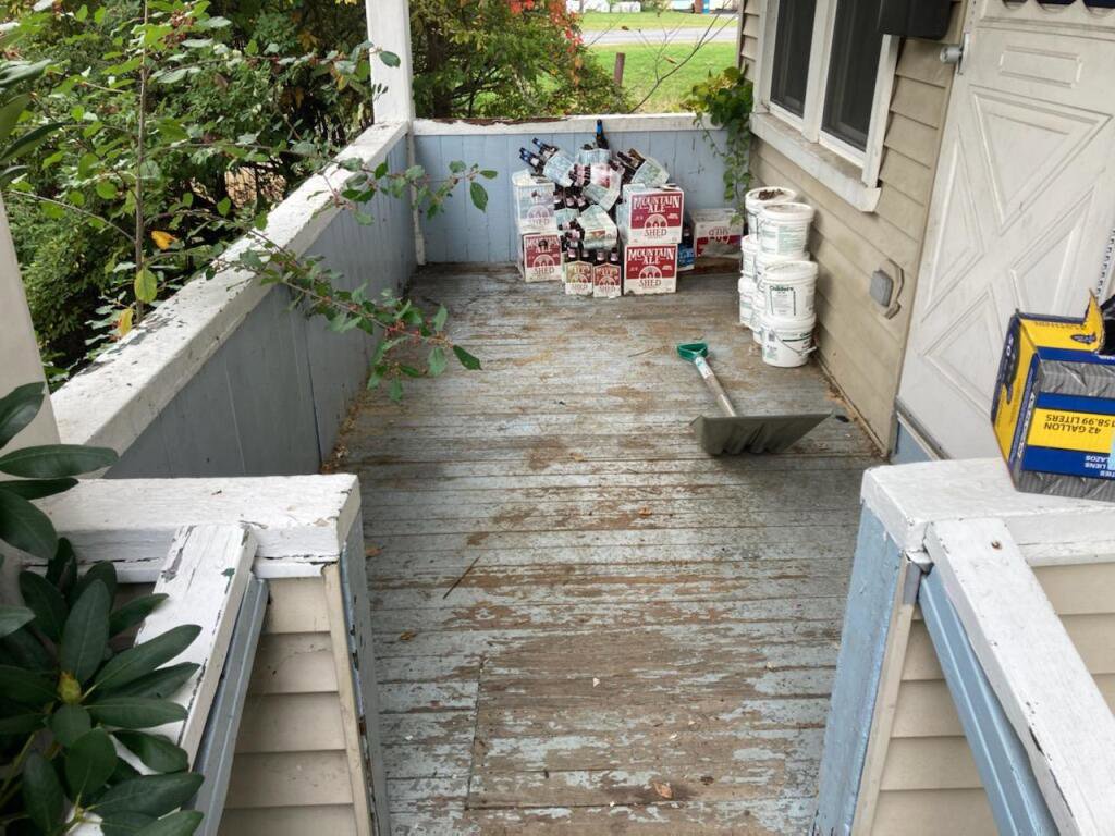 A porch with several paint cans and cardboard boxes, indicating items ready for junk removal by Rizzo Junk Removal in Nashua, NH.