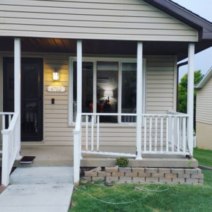 Front porch with damaged railing and concrete blocks, indicating a repair project by PRO HANDY FIXER in Kearney, NE.
