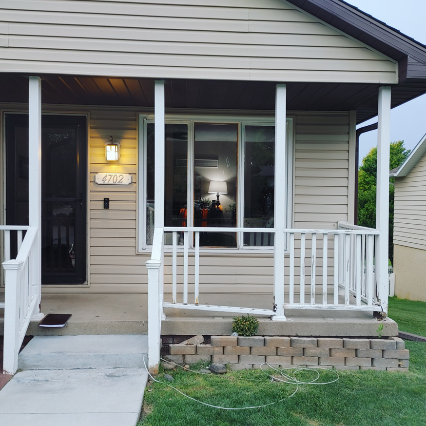 Front porch with damaged railing and concrete blocks, indicating a repair project by PRO HANDY FIXER in Kearney, NE.
