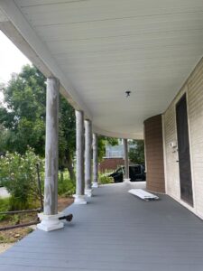 A renovated porch with a new gray floor, white columns, and soffit, completed by Usa Construction of Danbury LLC in Danbury, CT.