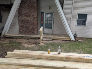 New wooden porch and walkway construction at a house, with lumber in foreground, by Handyman Service in Lafayette, IN.