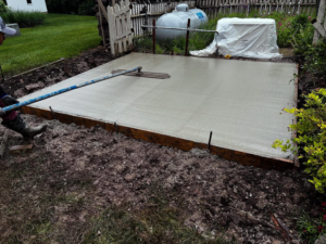 A worker pouring and finishing a concrete slab for a foundation or patio by Lafayette Concrete & Remodel, LLC in Lafayette, IN