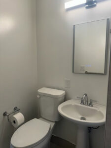 A refreshed powder room with a pedestal sink and new mirror installed by Dynamic Design & Remodeling in Westport, CT