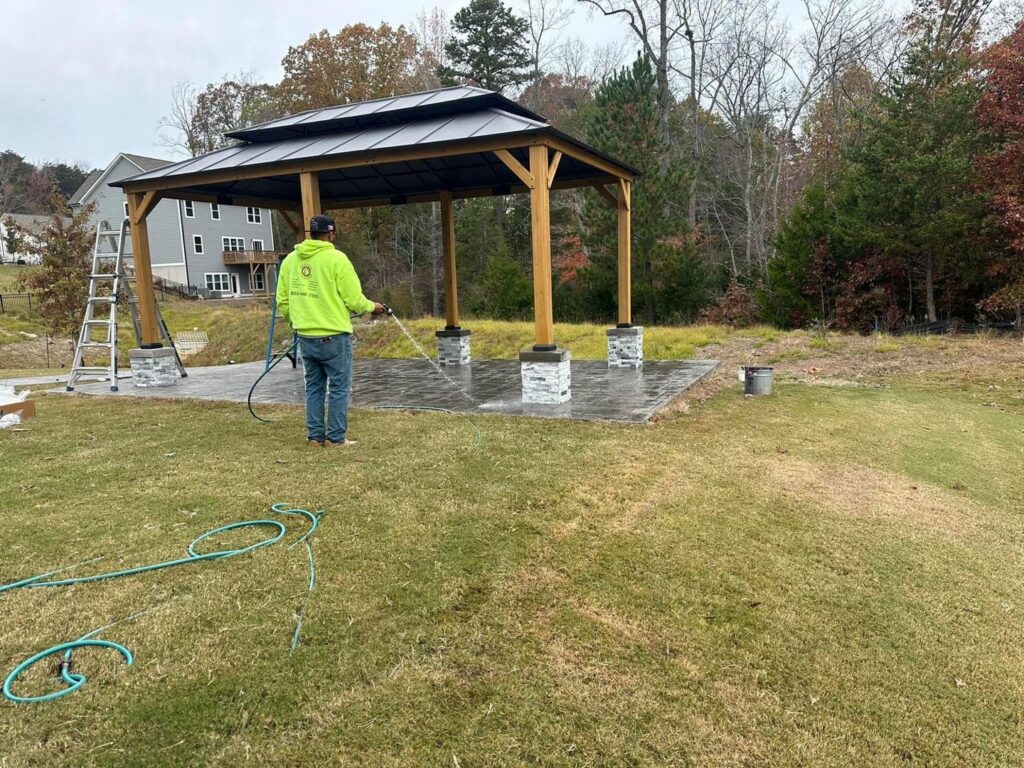 Worker power washing a newly installed patio and gazebo area by Solid Rock Builders in Rock Hill, SC.