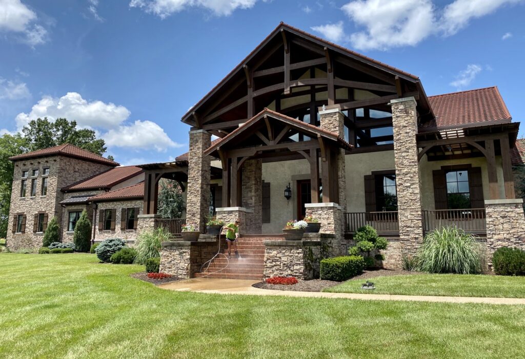 A Waterly, Co. Power Washing technician power washing stone steps and exterior of a large home in Nashville, TN.