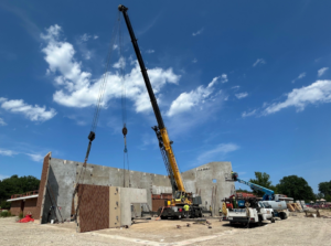 Construction workers installing precast concrete panels with a large crane for Lombard Architectural Precast Products Company in Aurora, IL.
