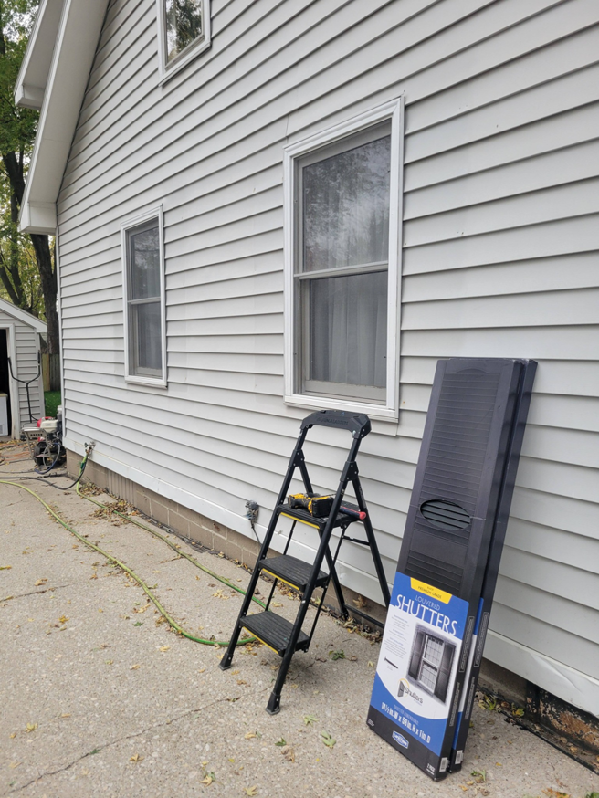 A house exterior with old shutters removed and new shutters in a box, showing preparation for installation by Cedar Valley Maintenance and Handyman Services LLC in Waterloo, IA.