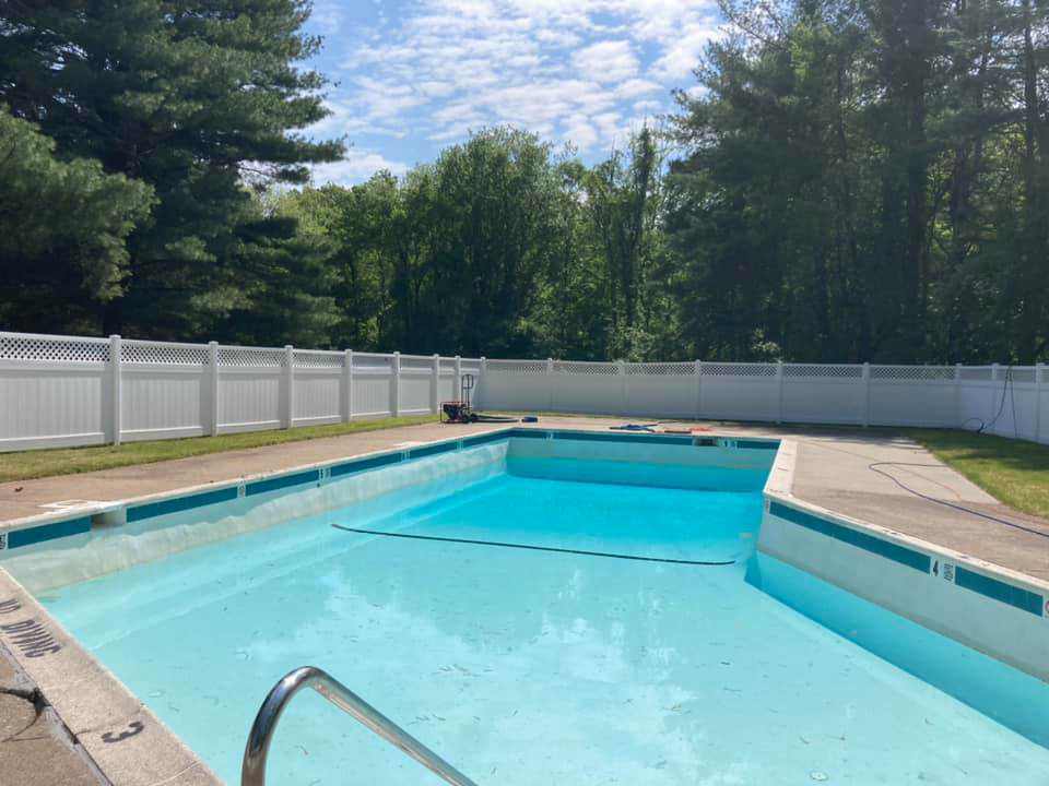 A pressure washer near a white fence by a swimming pool, indicating cleaning services by Connecticut Painting Group, Inc in North Haven, CT