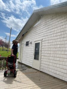 A handyman pressure washing the siding of a house, a service offered by SAM'S Handywork LLC in Independence, IA.