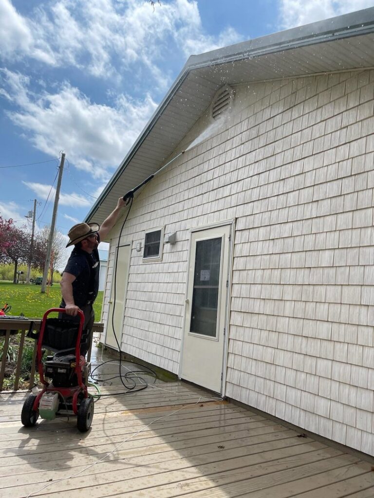A handyman pressure washing the siding of a house, a service offered by SAM'S Handywork LLC in Independence, IA.