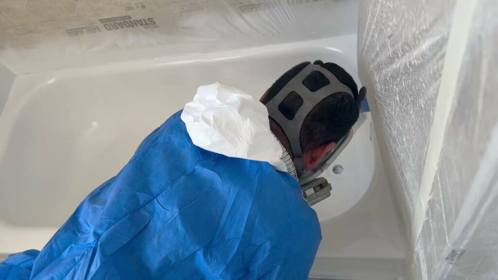 A professional refinishing technician working on a bathtub for Phillys Finest Tub & Tile Refinishing in Philadelphia, PA