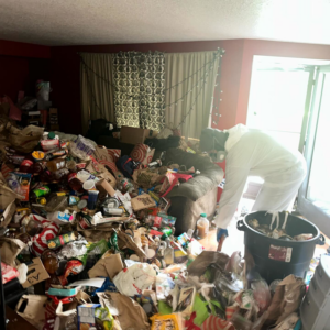 A professional in protective gear cleaning out a room filled with junk for Labor Loo in Newberg, OR.
