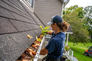 A professional worker removing leaves and debris from a residential gutter by The Brothers that just do Gutters in Sioux Falls, SD.