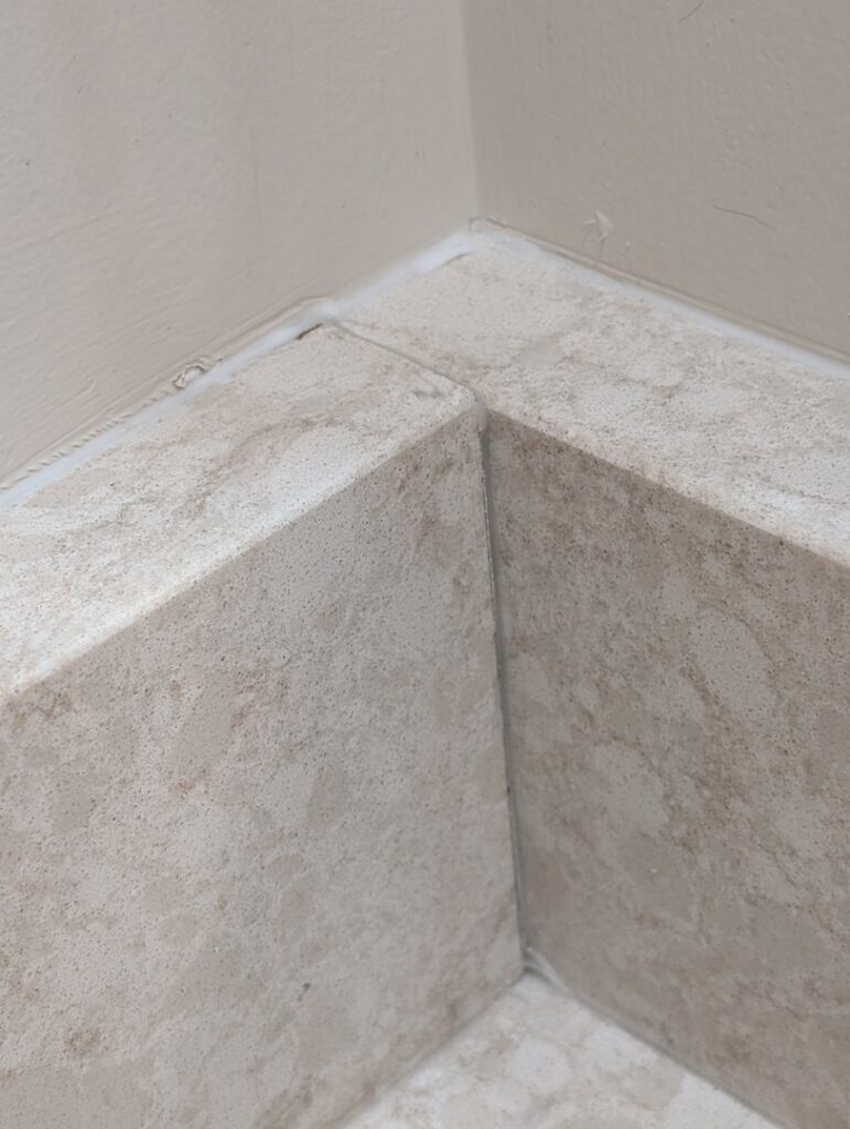 Close-up of expertly installed bathroom tiles in a corner, showcasing quality work by H4 Construction and Remodeling in Blue Springs, MO.