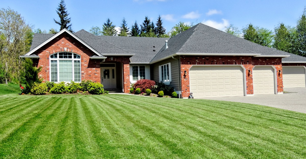 A professionally mowed and striped lawn in front of a house by Home and Land Services in Clarksville, TN