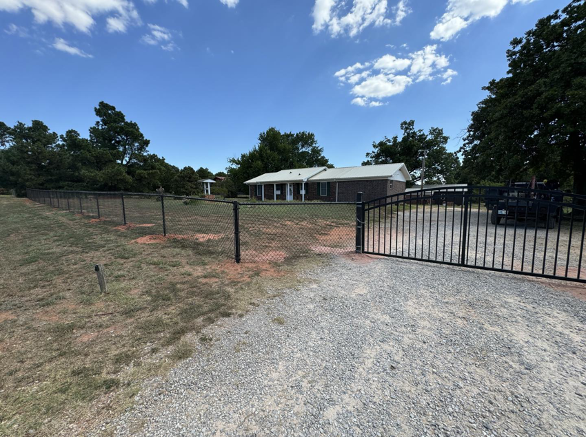 A wide view of a black chain-link fence and decorative gate at a property entrance by Herron Fencing LLC in Shawnee, OK.
