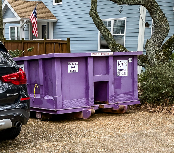 A purple dumpster from KT's Disposal parked in a residential driveway, ready for junk removal in Hampton, VA.
