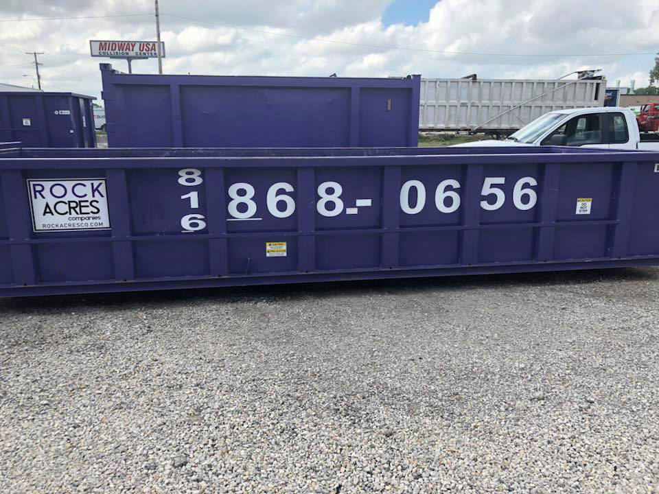 A purple roll-off dumpster with Rock Acres Companies branding in Kansas City, MO, ready for junk removal.