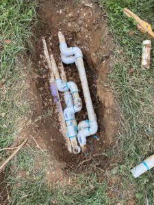 PVC pipes laid in a trench for an irrigation system installation by Rainscapes in Louisville, TN.