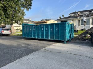 A Quality Bin Inc. dumpster being used for a roofing junk removal job on a street in Los Angeles, CA.