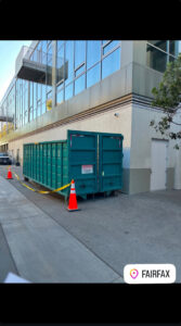 A Quality Bin Inc. dumpster placed next to a modern commercial building in Fairfax, Los Angeles, CA.