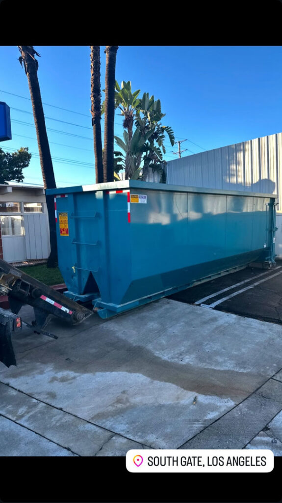 A Quality Bin Inc. dumpster being loaded or unloaded by a truck in South Gate, Los Angeles, CA.