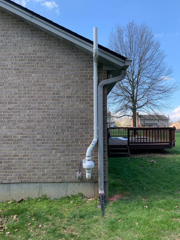 An exterior view of a newly installed radon mitigation system on a brick home by Velocity Radon Mitigation in Cincinnati, OH.