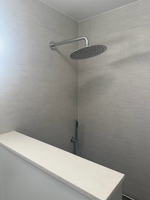 A newly installed rain shower head in a modern bathroom by Dynamic Design & Remodeling in Westport, CT