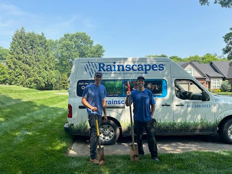 Two Rainscapes employees with shovels standing next to a company van in Louisville, TN.