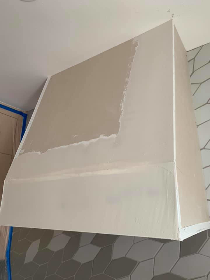 A custom range hood during the plaster application stage by Plasters of Italy in Plano, TX