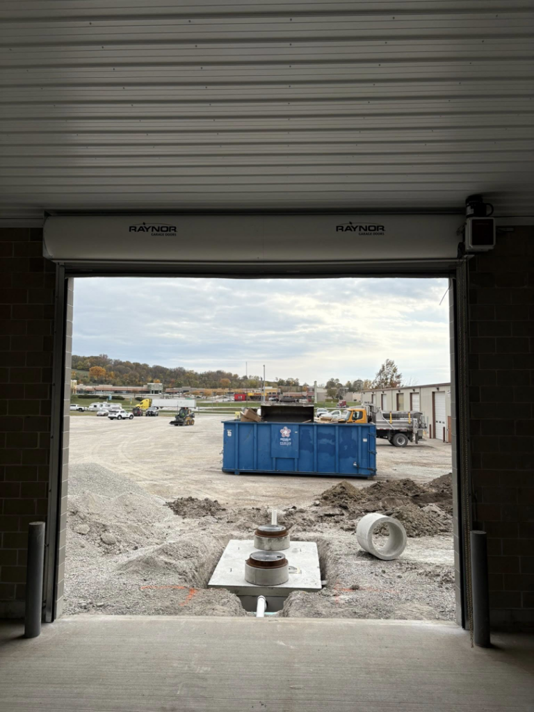 A Raynor commercial roll-up door partially closed, with excavation work outside, installed by Gateway Door and Contracting in House Springs, MO.