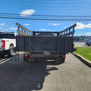 Rear view of a white Ford F450 flatbed truck with high metal cage sides, used for junk removal by Tri-State Carting, Inc in Bayville, NJ.
