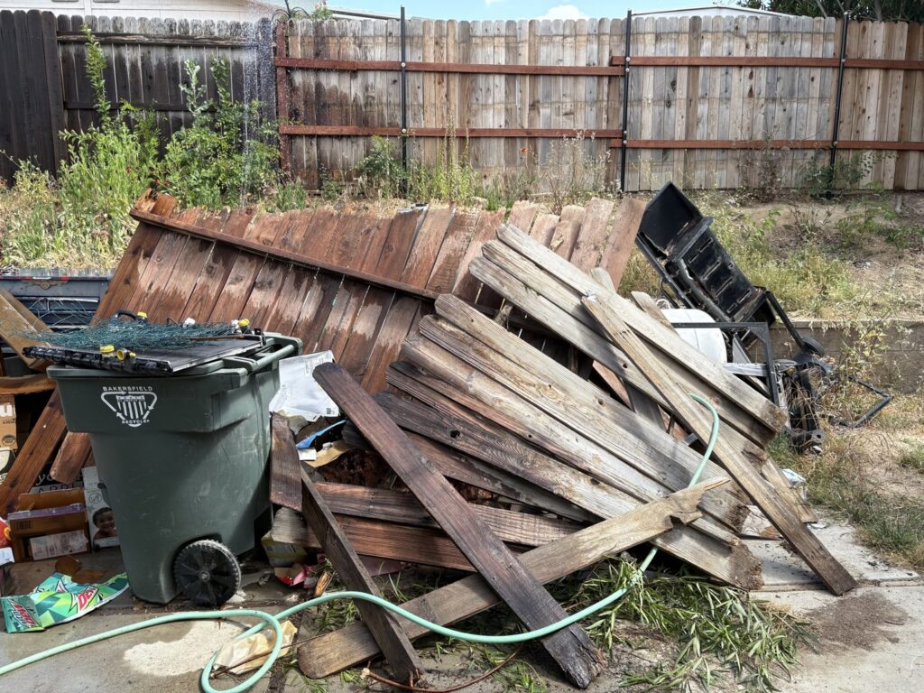 A recliner, refrigerator, and other bulky items piled up against a house for junk removal by Area 661 Hauling in Bakersfield, CA.